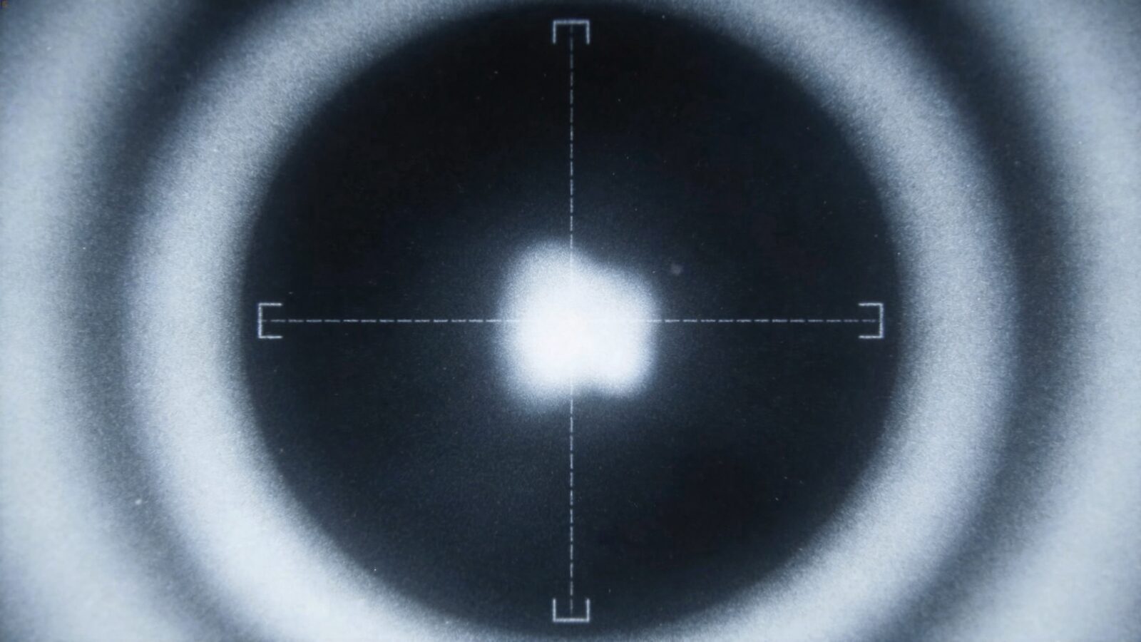Illustration: a grainy infrared camera frame with a crosshair and tracking brackets around a bright, blurry heat blob — in the style of a targeting camera, no readable text.